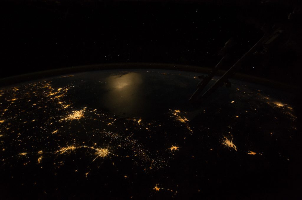 Cities, moonlight, and fossil-fuel industries frame the Gulf of Mexico with light.