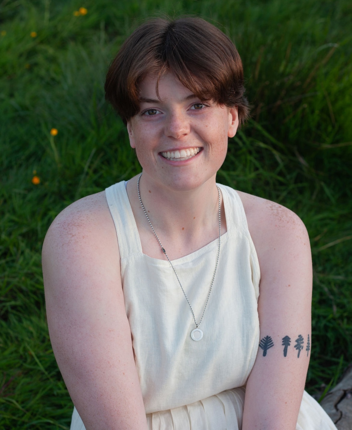 Picture of Emma wearing a white dress in a green grass field.