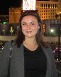 Photo of Freja in front of a well-lit background in Las Vegas, wearing a grey coat and black shirt.