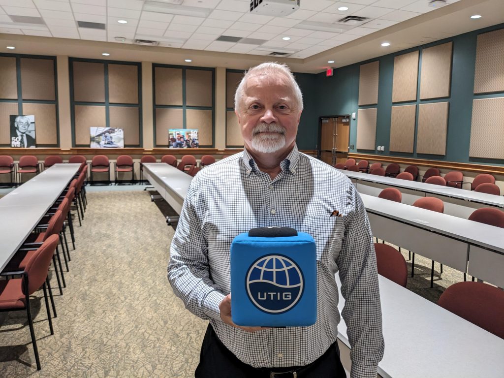 Photo of Tim holding the UTIG Cube of Truth in the seminar room.