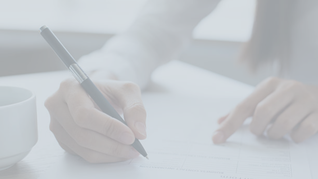 Stock image of someone signing a form. They are holding a black pencil in their hand.
