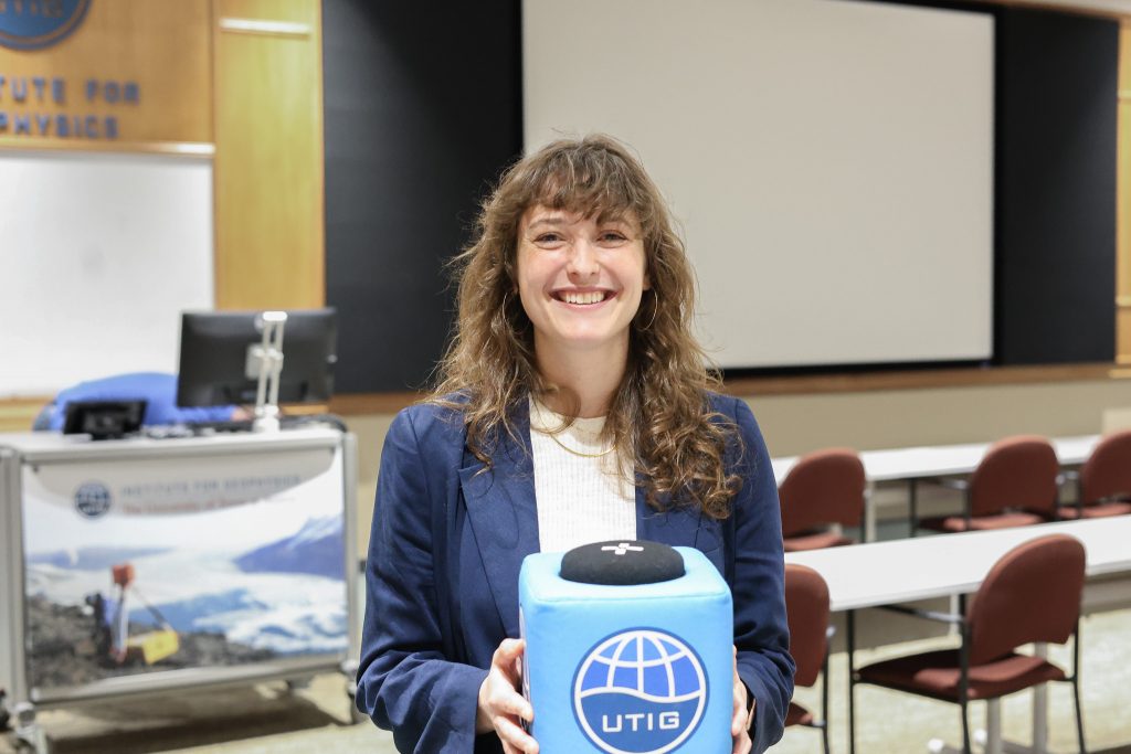 Photo of Allie holding the UTIG Cube of Truth in the UTIG seminar room.