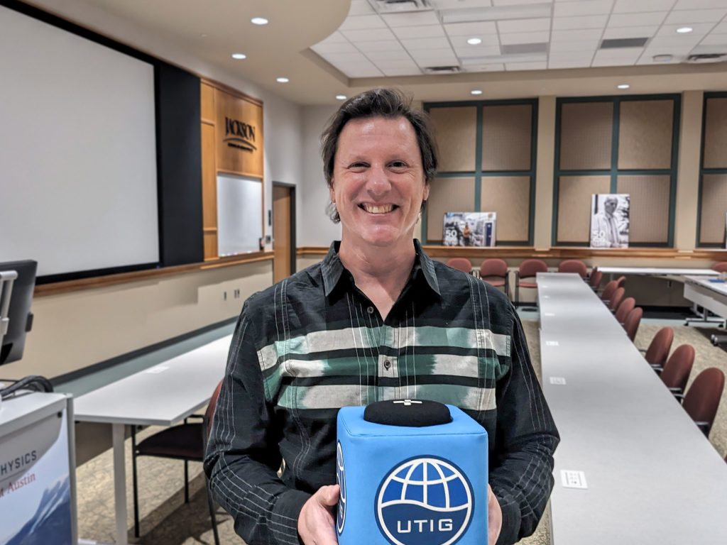 Photo of Jud holding the UTIG Cube of Truth in the UTIG seminar room.