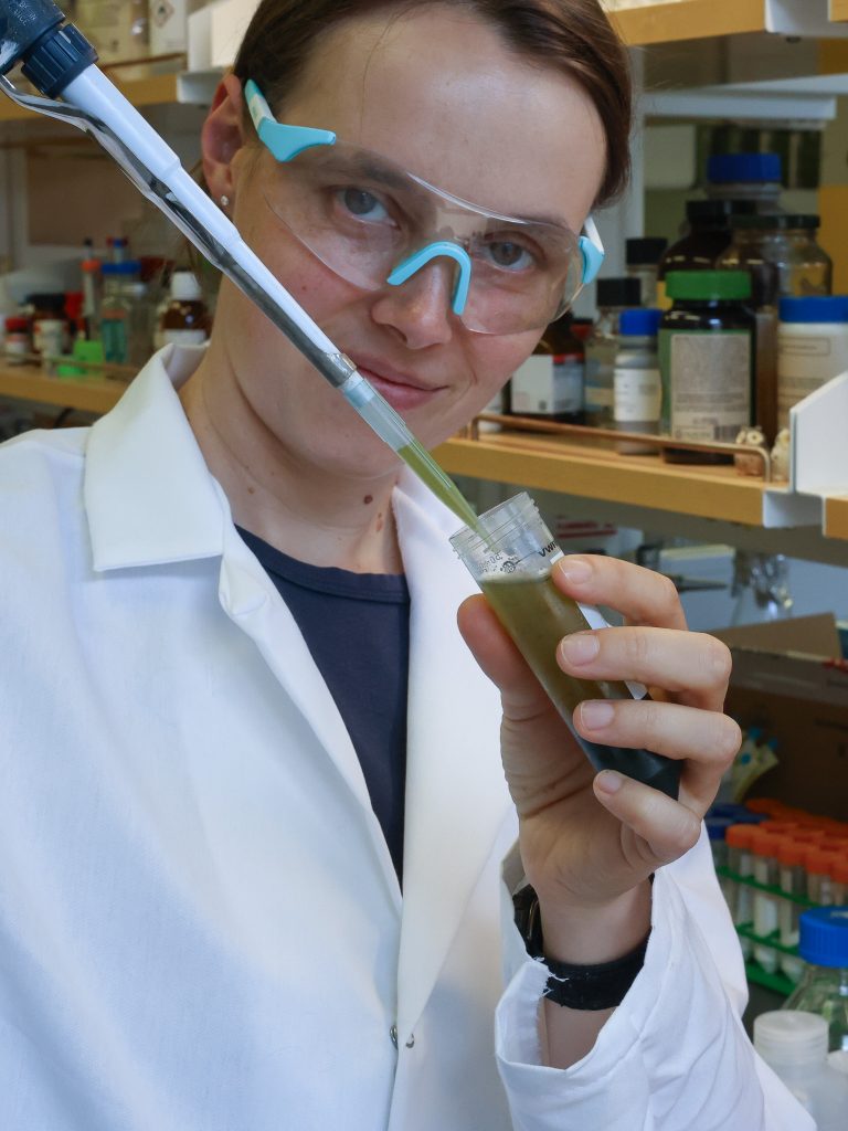 Photo of Cornelia. She is wearing personal protective equipment, and is holding a pipette.