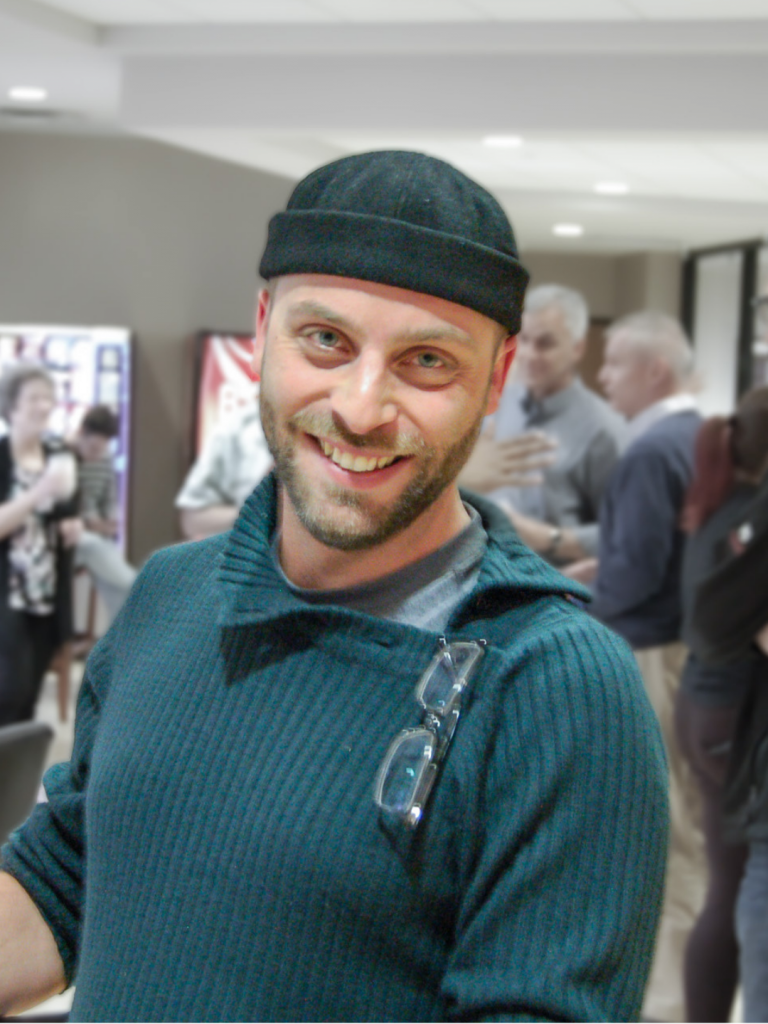 Photo of Cyril. He is wearing a beanie, and a blue shirt.