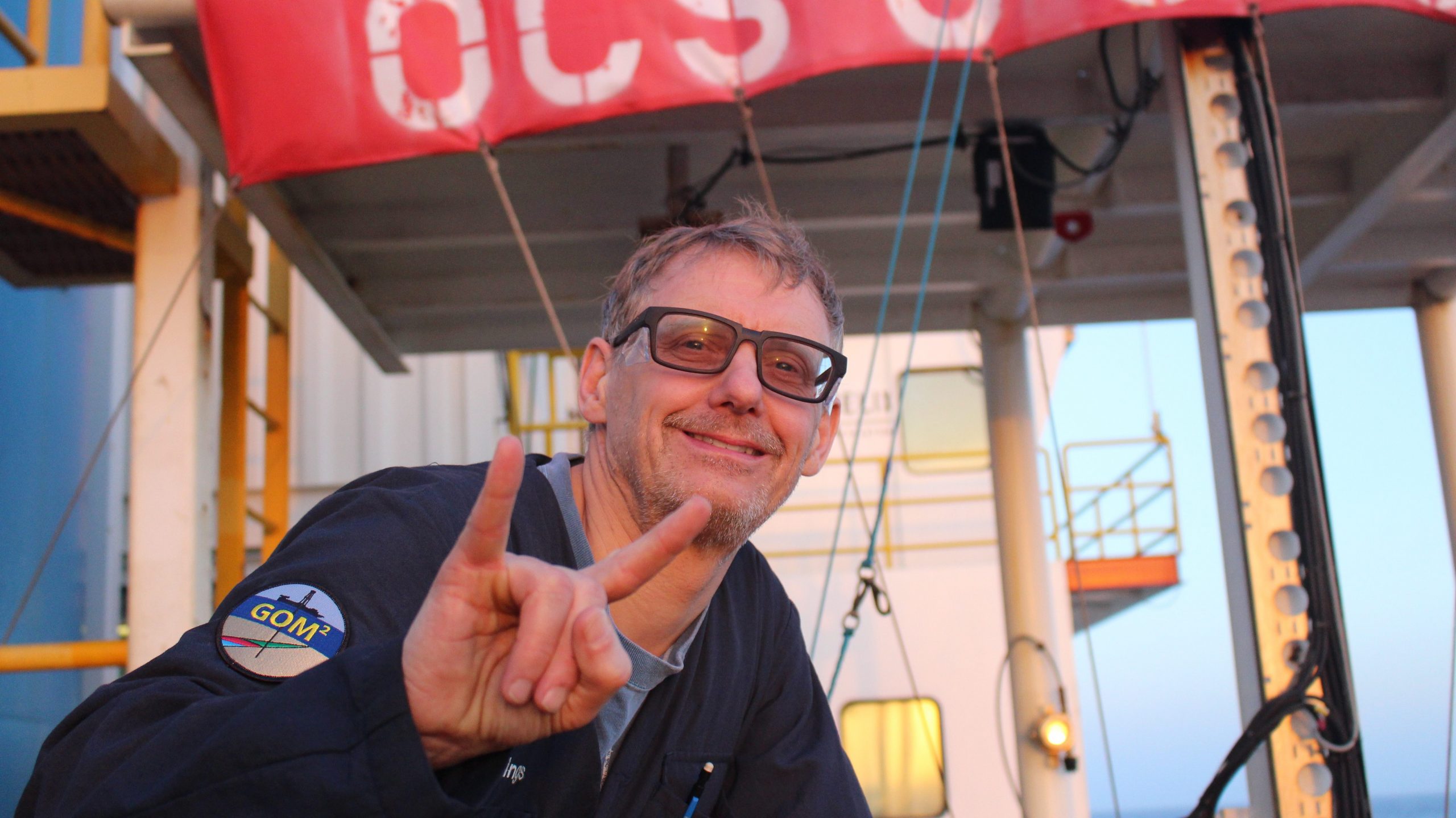 A photo of Peter Flemings with the deck of the deep-water coring vessel behind him.