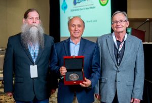 GCSSEPM President James Willis (left) and John Snedden (right) present Michael Sweet with the Doris Malkin Curtis Award at the recent GCAGS/GCSSEPM GeoGulf 2026 convention in Baton Rouge. Photo courtesy of the Gulf Coast Association of Geological Societies